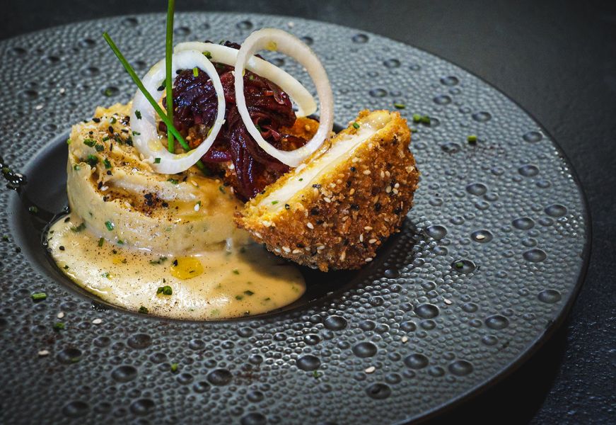 Canederli con cipolla e formaggio impiattati con salsa cremosa