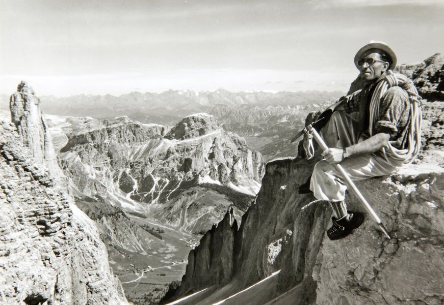 Storica foto di alpinista seduto su una cima con vista panoramica sulle Dolomiti